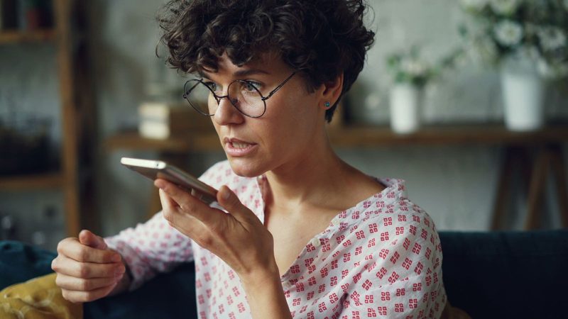 Mujer hablando al asistente de voz de su teléfono móvil